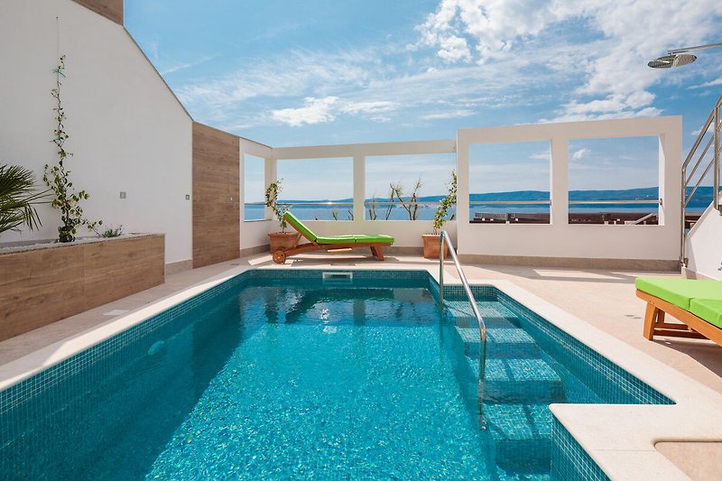 Schönes Ferienhaus mit Pool, blauem Himmel und bequemen Möbeln.