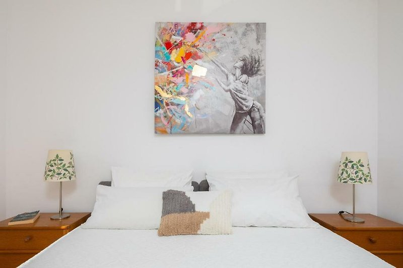 Stylish bedroom with comfortable bed, vibrant decor, and modern art.