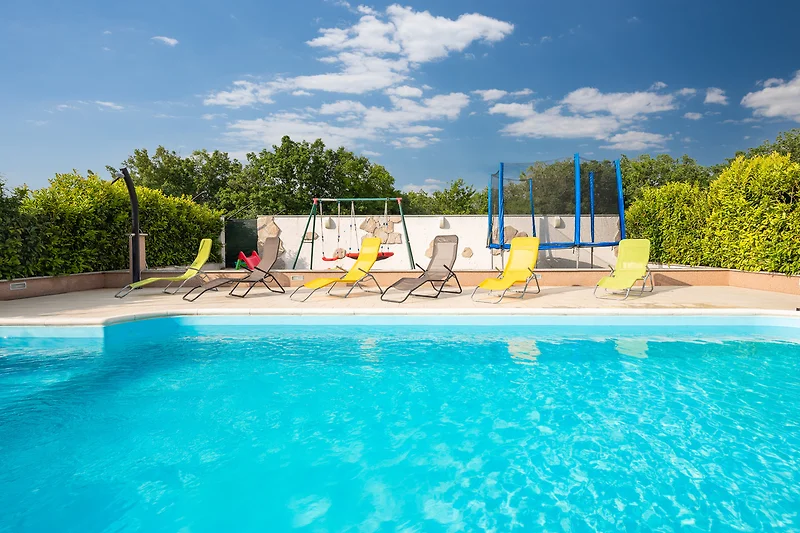 Villa mit Pool, Outdoor-Möbeln und schattigem Bereich.