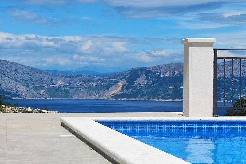 Stunning poolside view with azure water, mountain backdrop, and clear skies.