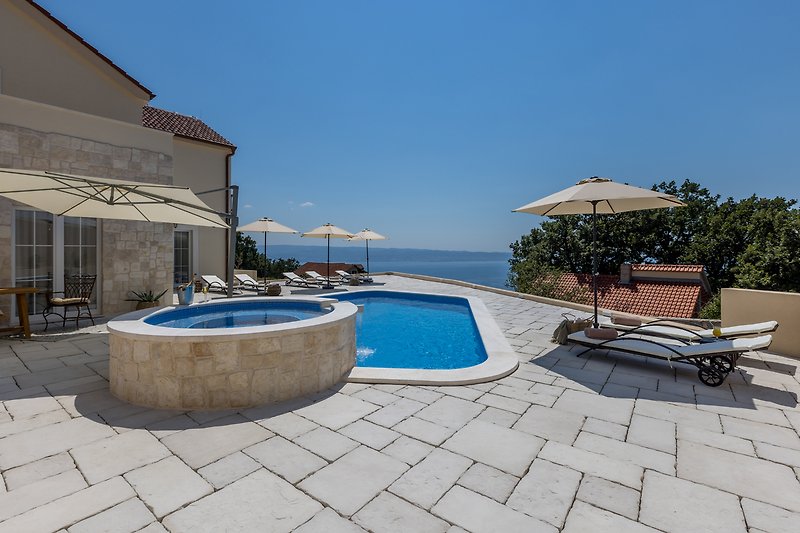 Luxury seaside resort with pool, ocean view, and outdoor furniture.