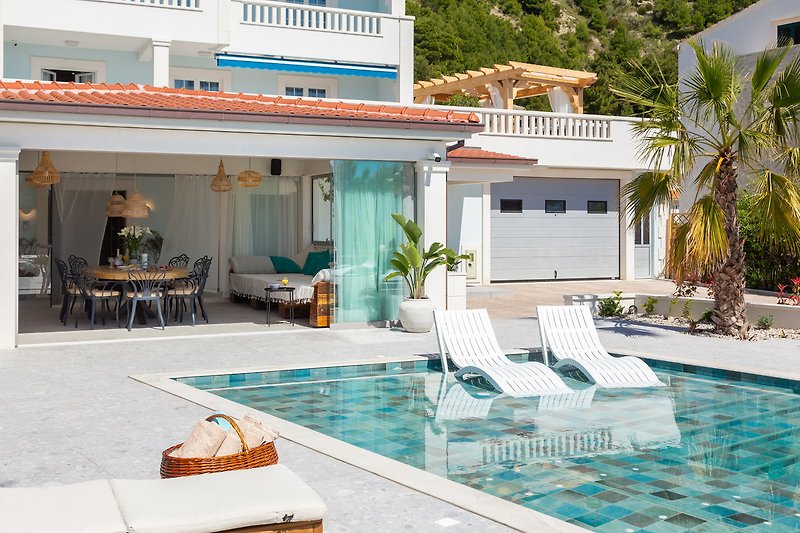 Luxuriöser Pool mit Sonnenliegen und Palmen.