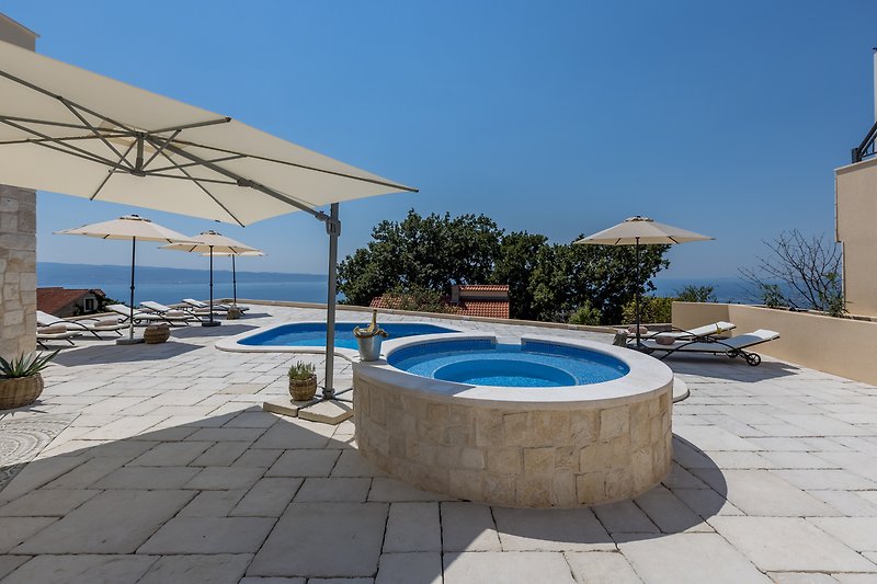 Stylish seaside resort with azure pool, sunloungers, and ocean view.