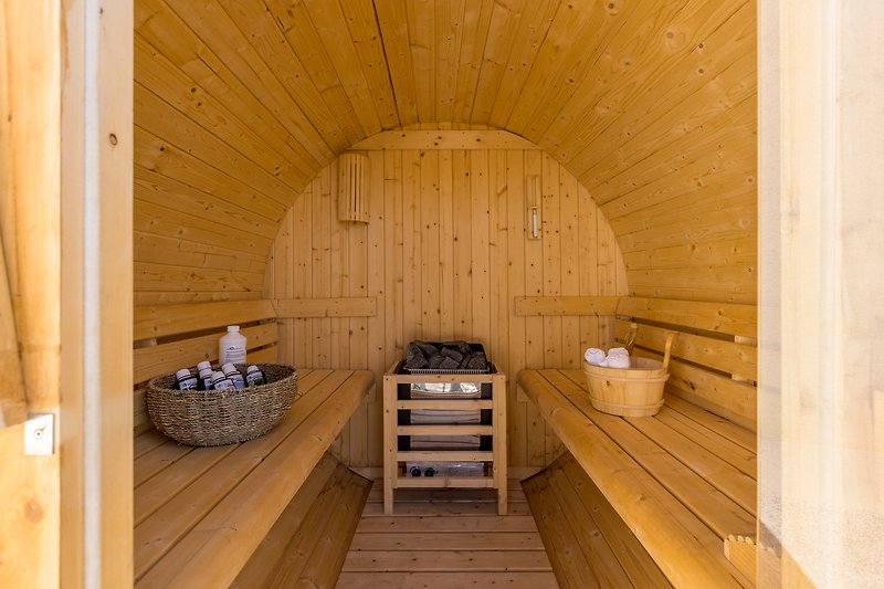 Rustic sauna with wooden beams and barrel.