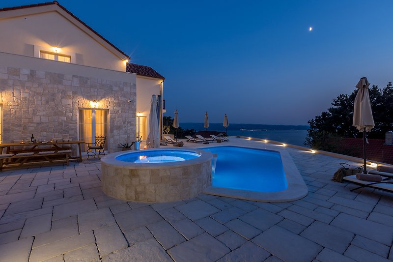 Stunning seaside resort with pool, ocean view, and beautiful lighting.