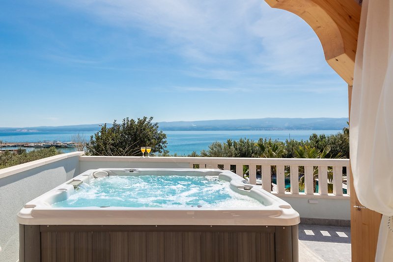 Luxuriöser Pool mit Holzdeck und Blick auf den Ozean.