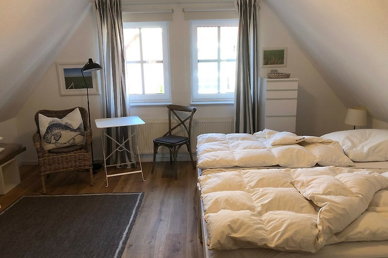 Gemütliches Schlafzimmer mit Holzboden und großem Fenster.