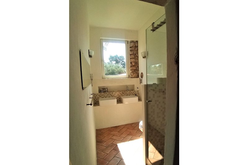 Bad mit Dusch-Glaskabine und WC dahinter , 2 Waschbecken unter Fenster zum südlichen Garten