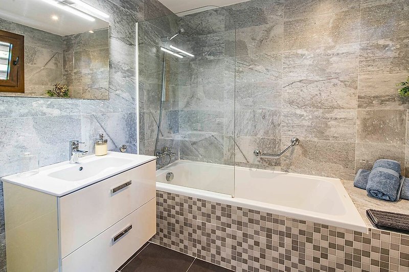 Modernes Badezimmer mit Spiegel, Dusche und Pflanze.