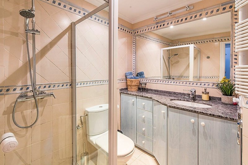 Modernes Badezimmer mit Holzakzenten, Dusche und Pflanzen.