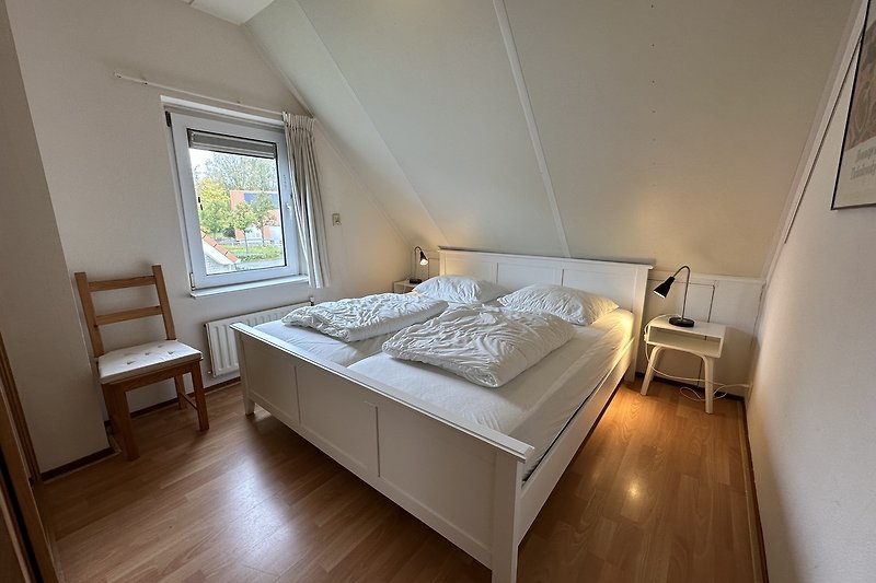 Gemütliches Schlafzimmer mit Holzbett und Fenster.
