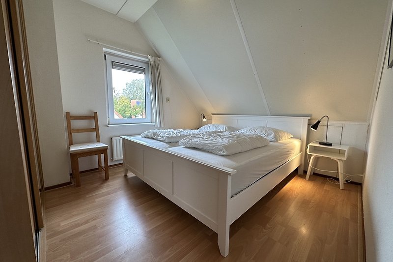 Gemütliches Schlafzimmer mit Holzbett und Fensterbehandlung.