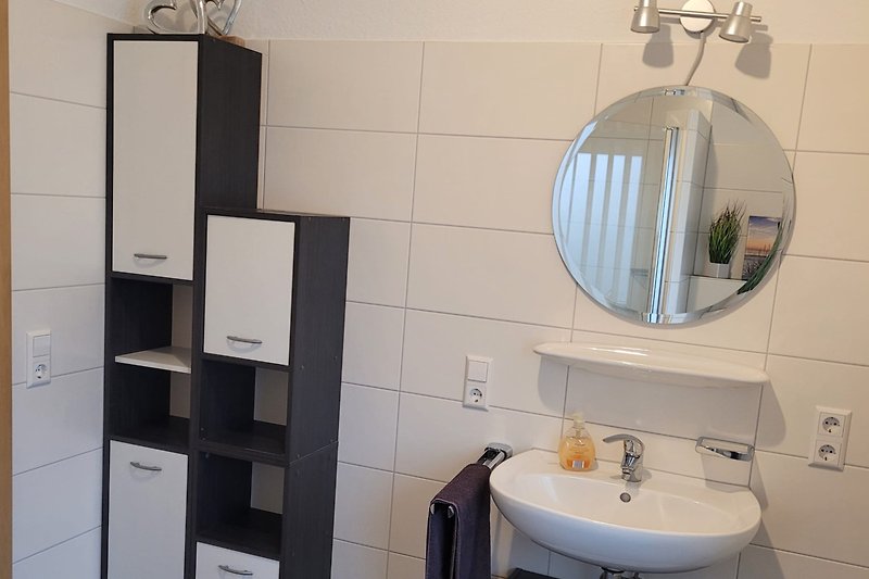 Schönes Badezimmer mit Spiegel, Waschbecken und Schränken.
