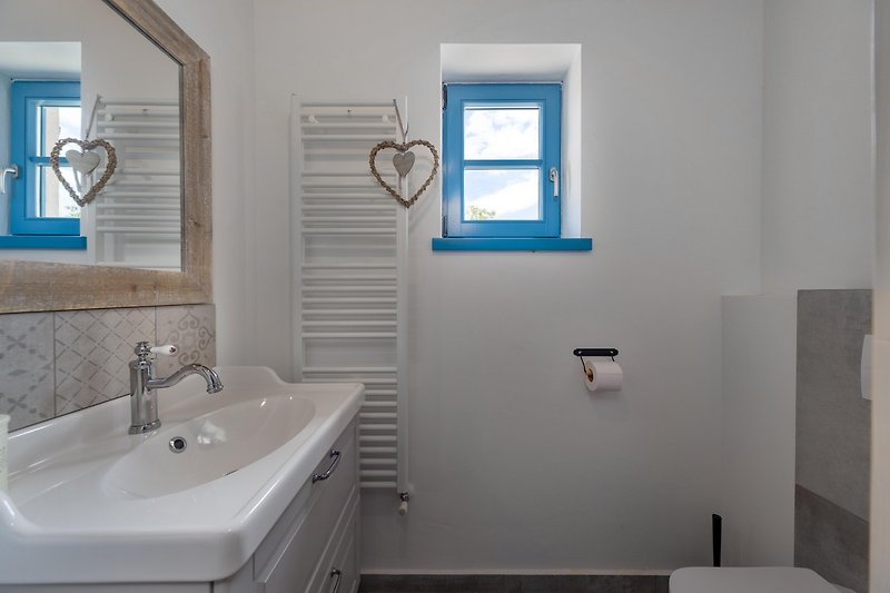 Luksuzna kupaonica s plavim umivaonikom i drvenim prozorom.
