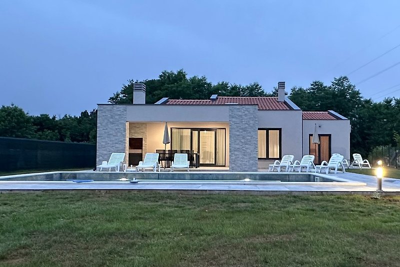 Charmantes Bauernhaus mit Veranda, grünem Garten und Bäumen.