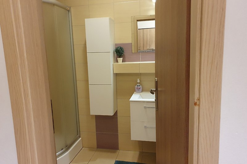 Schönes Badezimmer mit Holzboden, Spiegel und Waschbecken.