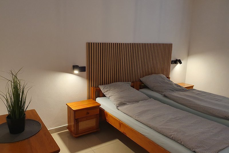Gemütliches Schlafzimmer mit bequemem Bett, Holzmöbeln und schöner Beleuchtung.