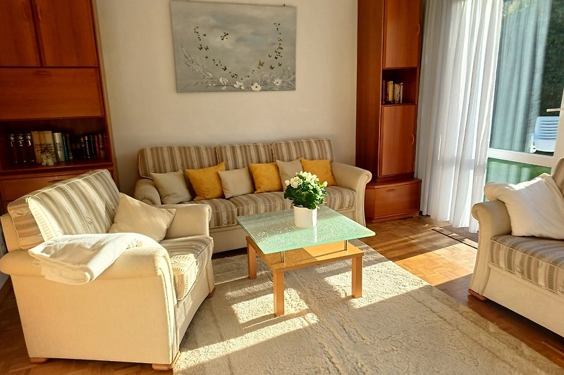 Gemütliches Wohnzimmer mit Holzinterieur, großen Fenstern und schönen Pflanzen. Perfekt zum Entspannen.