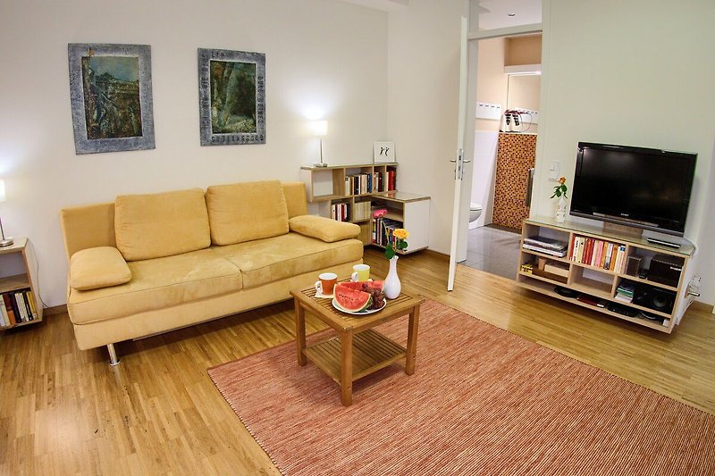 Gemütliches Wohnzimmer mit bequemer Couch, stilvollem Mobiliar und Fernseher.