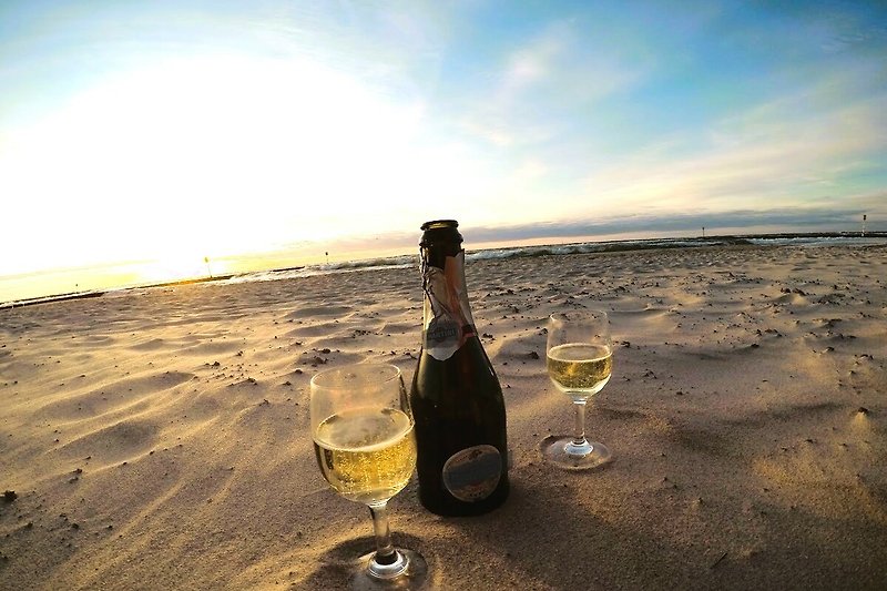 Ein idyllischer Strand mit einem atemberaubenden Sonnenuntergang und einem Glas Wein.