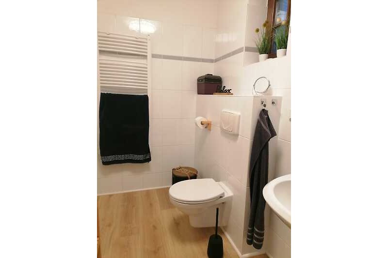 Gemütliches Badezimmer mit lila Akzenten und Holzboden.