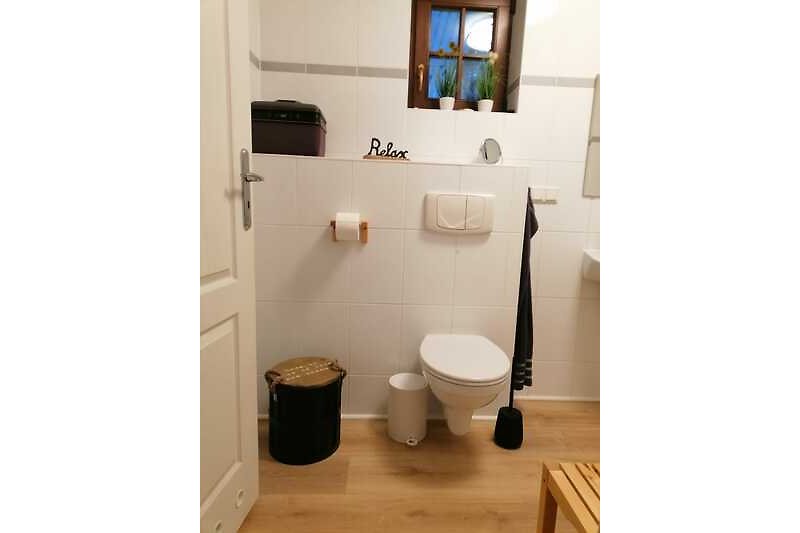 Schönes Badezimmer mit Holzboden, Fenster und Toilette.