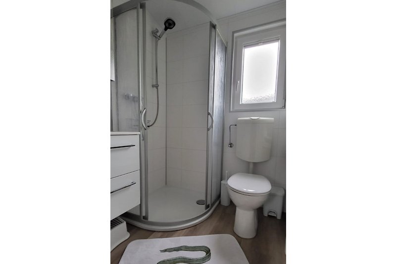 Modernes Badezimmer mit rechteckigem Fenster und Toilette.