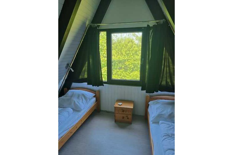 Gemütliches Schlafzimmer mit Fenster, Pflanzen und bequemem Bett.