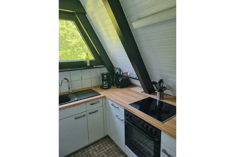 Moderne Küche mit Holzschränken, Arbeitsplatte und Spülbecken.