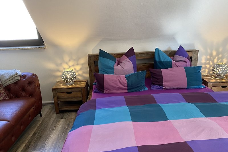 Gemütliches Schlafzimmer mit violetten Kissen und Holzbettgestell.
