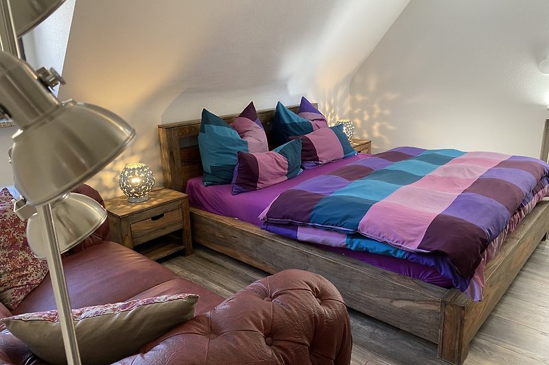 Gemütliches Schlafzimmer mit lila Kissen und Holzbett.