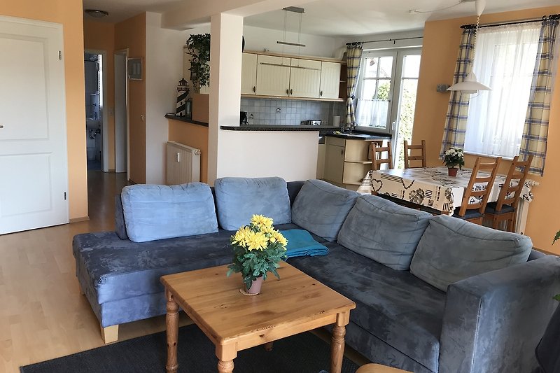 Wohnbereich mit Couch, Esstisch und offener Küche