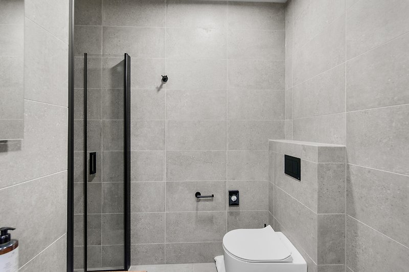 Schwarzes Badezimmer mit Dusche, Waschbecken und Armaturen.