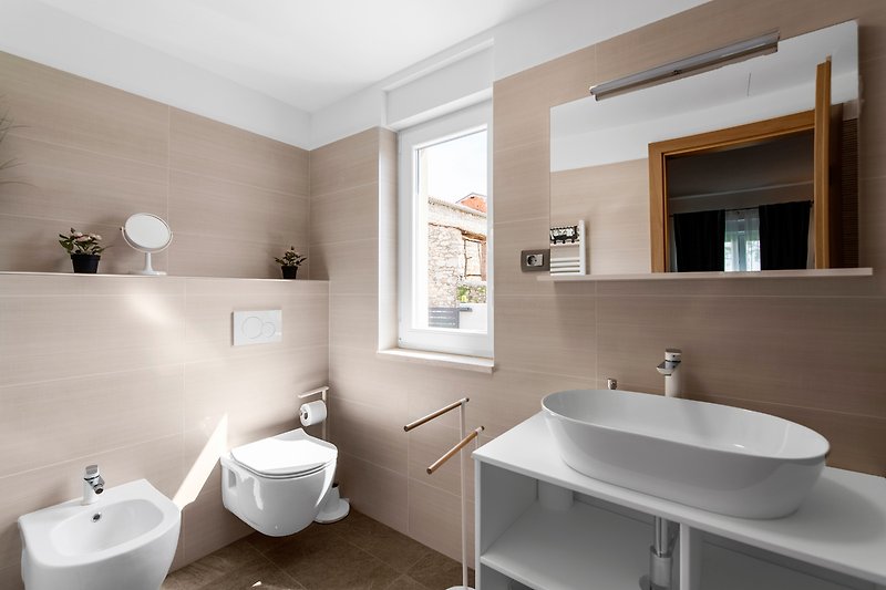 Modernes Badezimmer mit hellem Spiegel und Waschbecken.