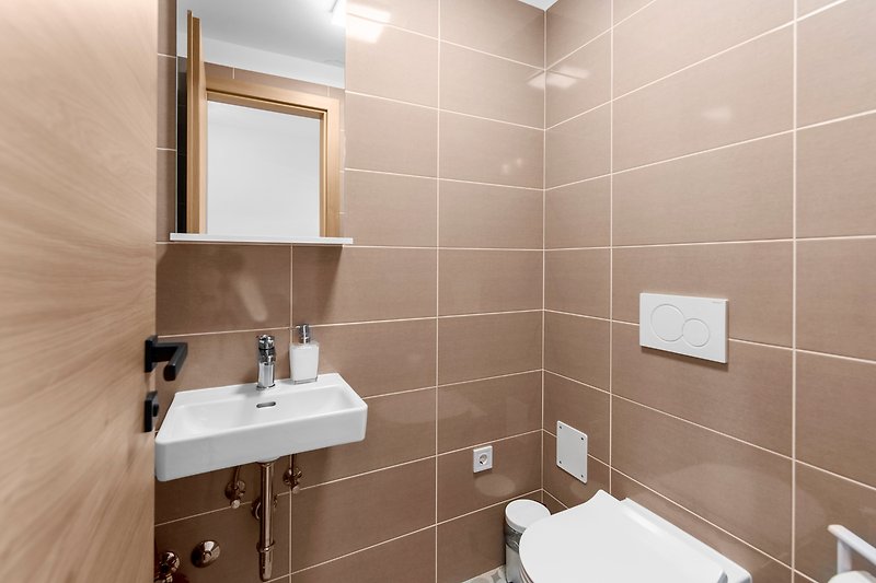 Modernes Badezimmer mit elegantem Spiegel, Waschbecken und Armaturen.