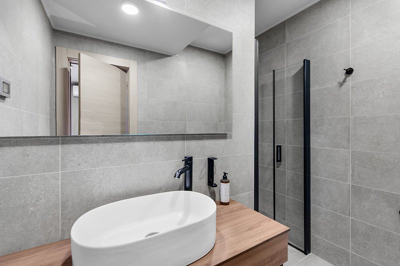 Modernes Badezimmer mit schwarzen Armaturen und Spiegel. Edle Einrichtung.