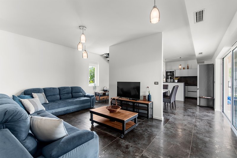 Stilvolles Wohnzimmer mit bequemer Couch, Holztisch und moderner Beleuchtung.