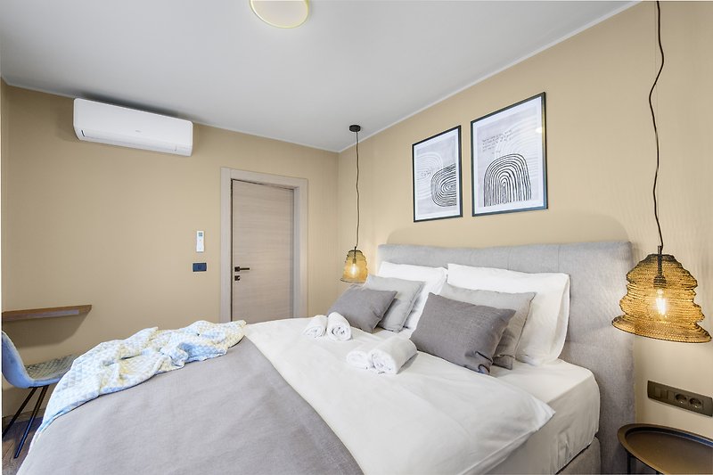 Modernes Schlafzimmer mit hellem Holzbett und stilvoller Beleuchtung.