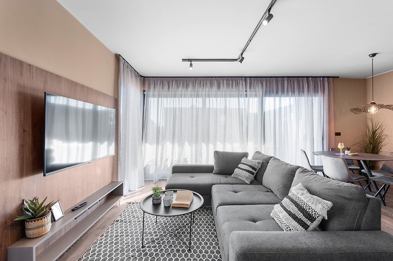 Wohnzimmer mit bequemer Couch, Pflanze und moderner Einrichtung.