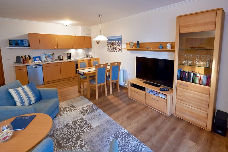 Gemütliches Wohnzimmer mit blauem Sofa, Holzmöbeln und Fernseher.