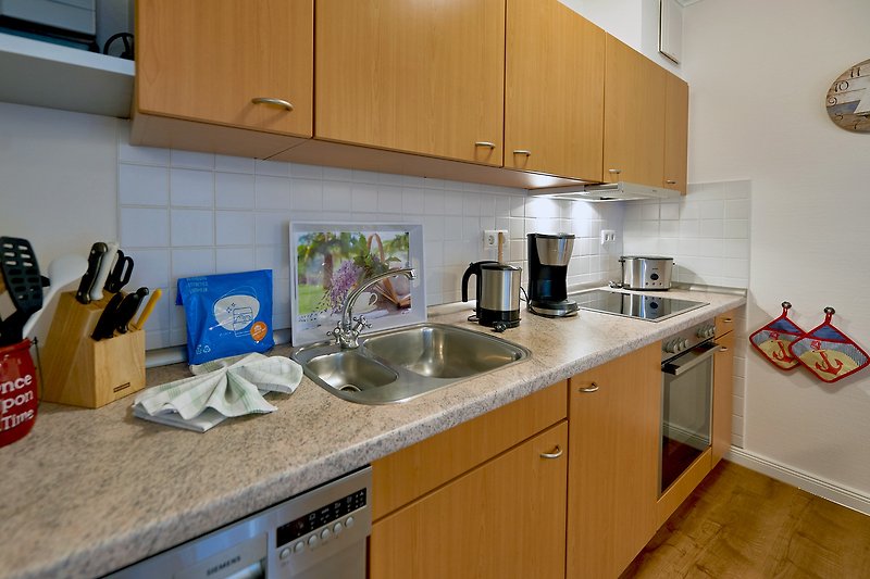 Gemütliche Küche mit Holzschränken, Spüle und Arbeitsplatte.