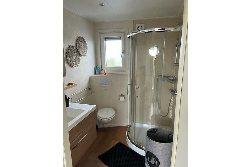 Modernes Badezimmer mit weißem Waschbecken, Dusche und Akzenten.