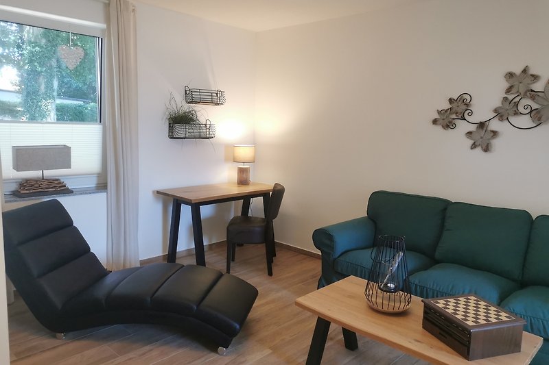 Wohnbereich mit Couch, Relaxliege und kleinem Arbeitsplatz