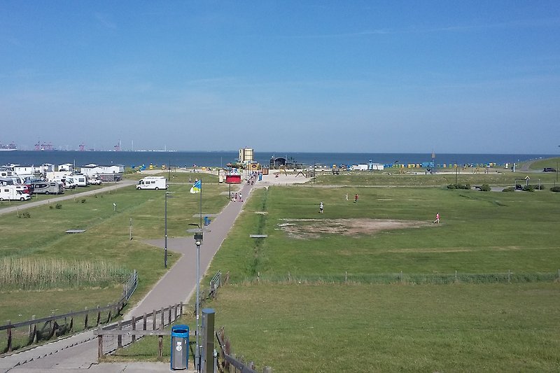 Blick vom Deich auf den Tossener Strand mit großem Spielplatz und Gastronomie in Tossens