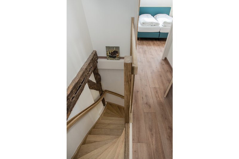 Holztreppe mit Handlauf in hellem Raum.