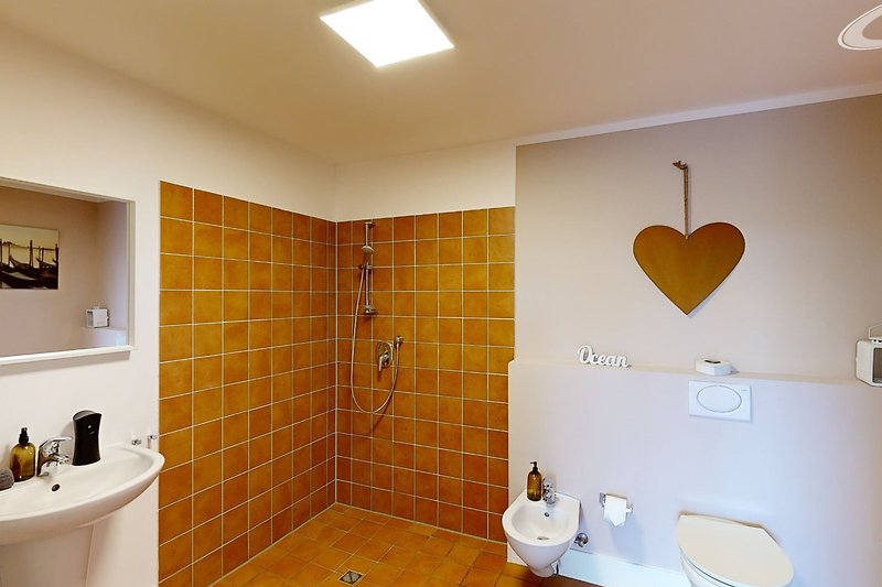 Modernes Badezimmer mit gelber Beleuchtung und Keramik.