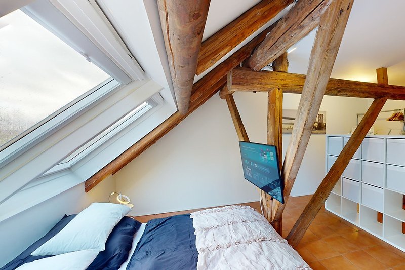 Holzhaus mit Dachfenster, gemütlichem Bett und Holzleiter.