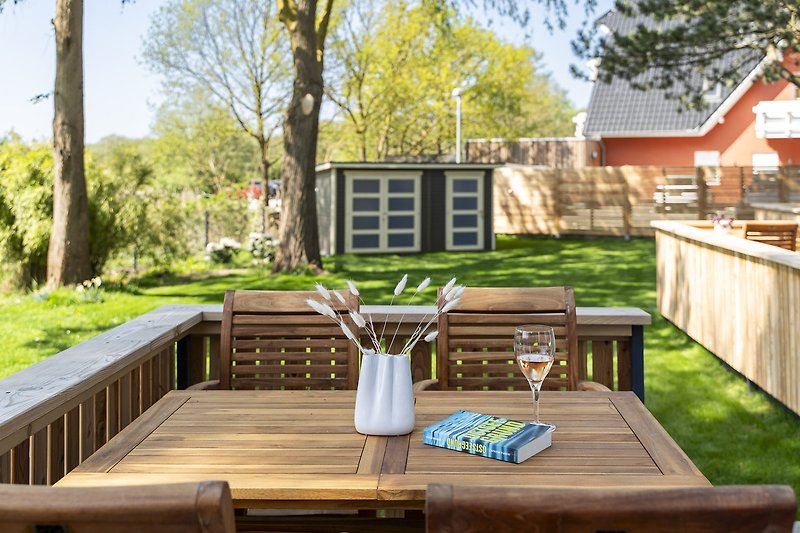 Gemütlicher Garten mit Holzterrasse, Pflanzen und Gartenmöbeln.