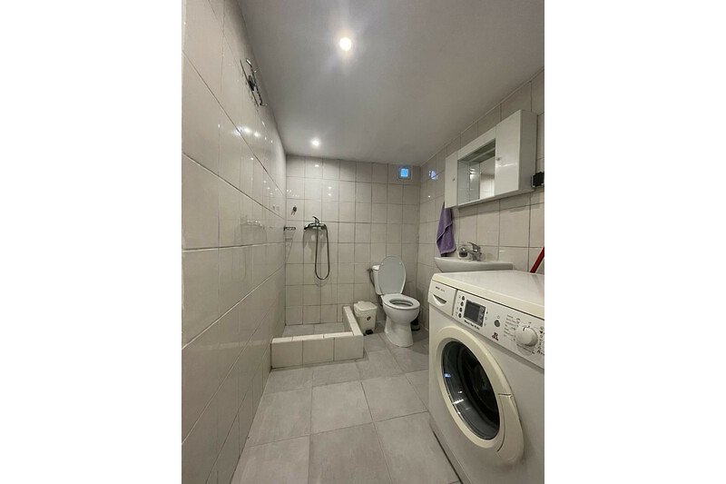 Moderne Badezimmer mit Dusche, Waschmaschine und Trockner.