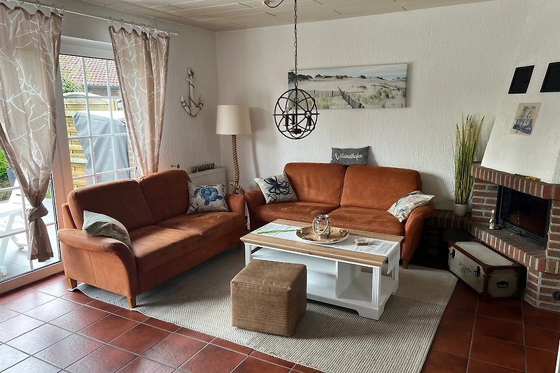 Gemütliches Wohnzimmer mit Holzmöbeln, Couch und Tisch. Entspannte Atmosphäre mit Bilderrahmen und Pflanzen.